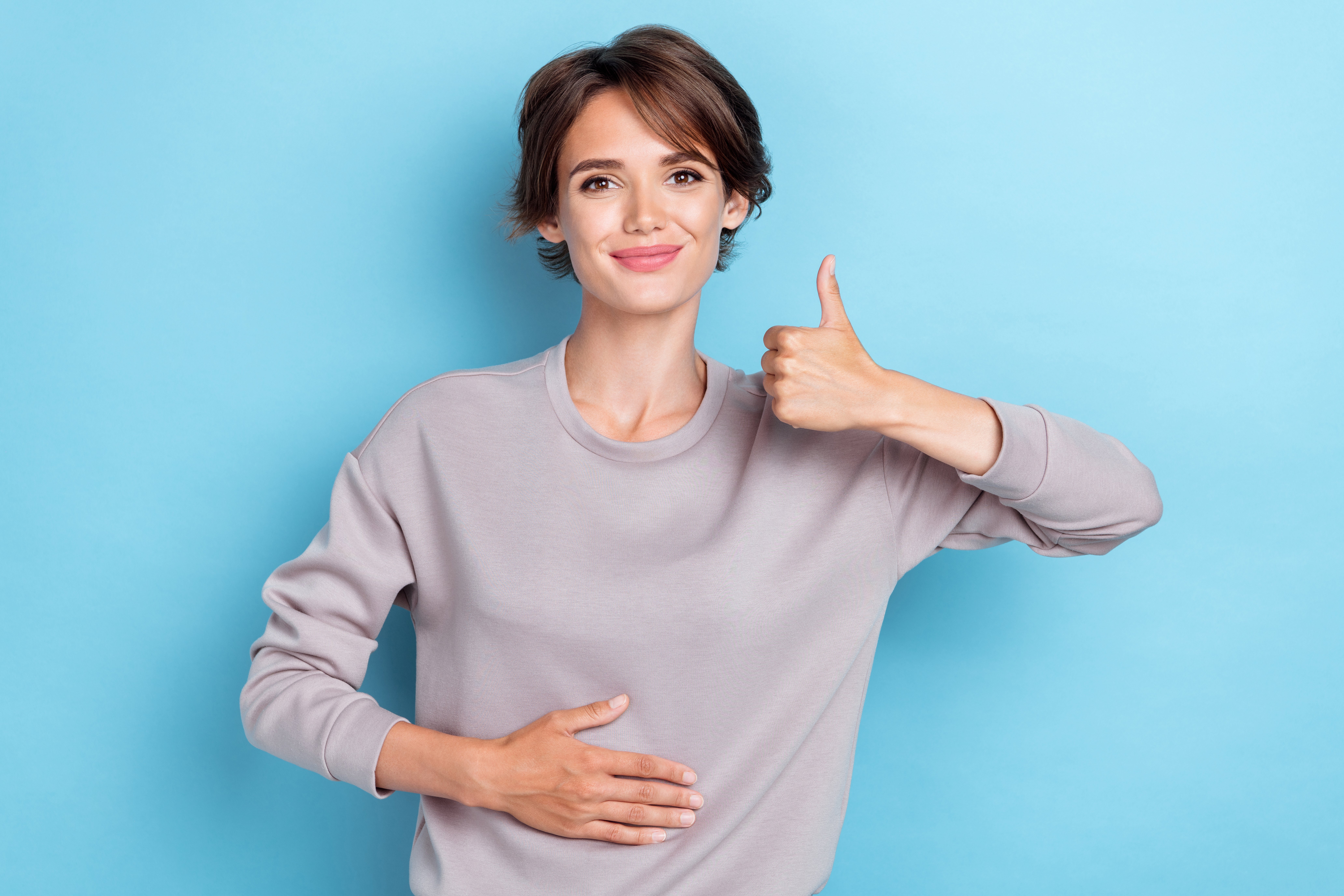 Appetit anregen: Eine glückliche Frau, die ihre Hand auf ihrem Bauch hat.