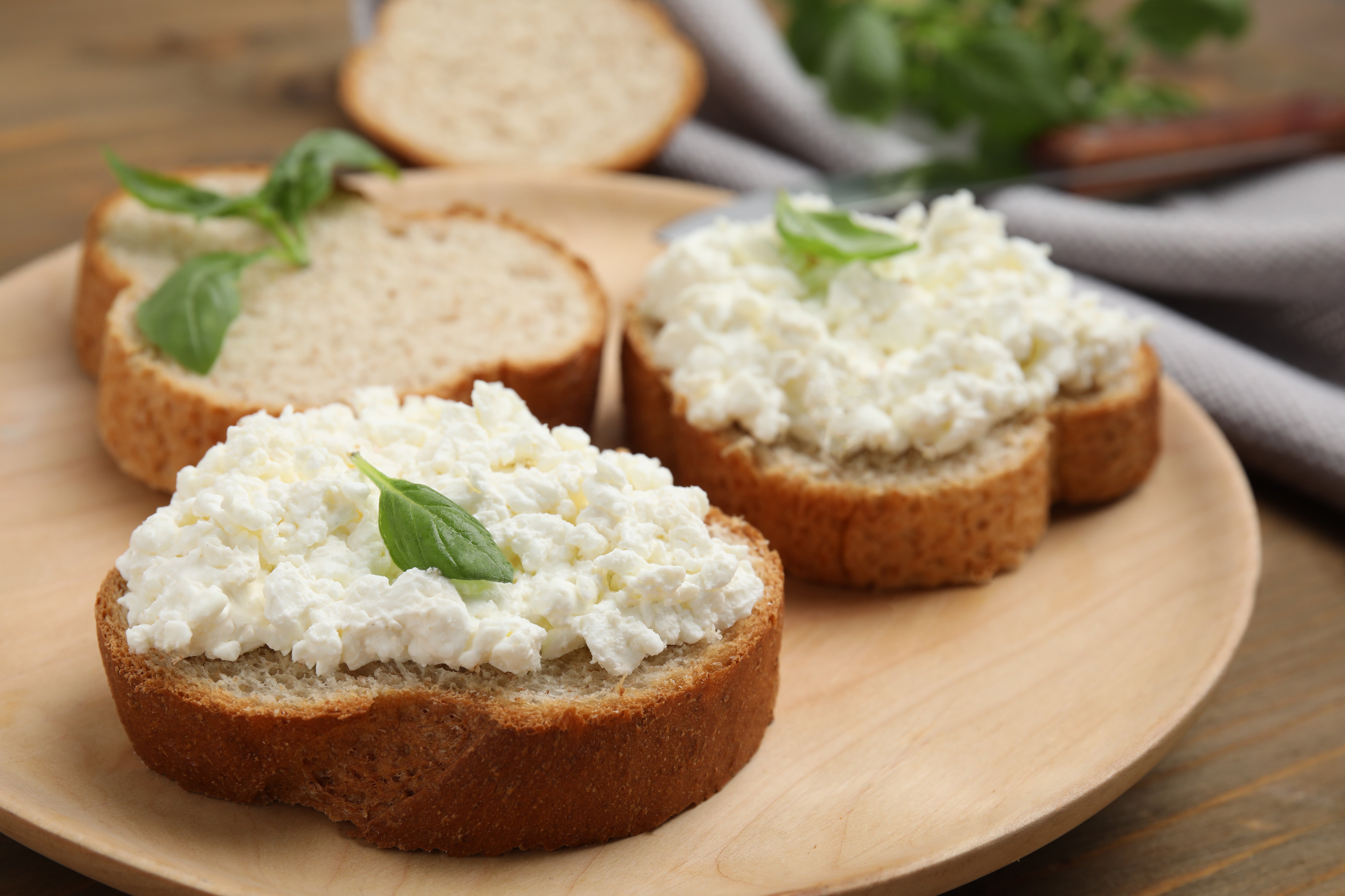 Brot mit Hüttenkäse Vollkornbrote mit Hüttenkäse auf einem Holzuntergrund und verziert mit Basilikum.