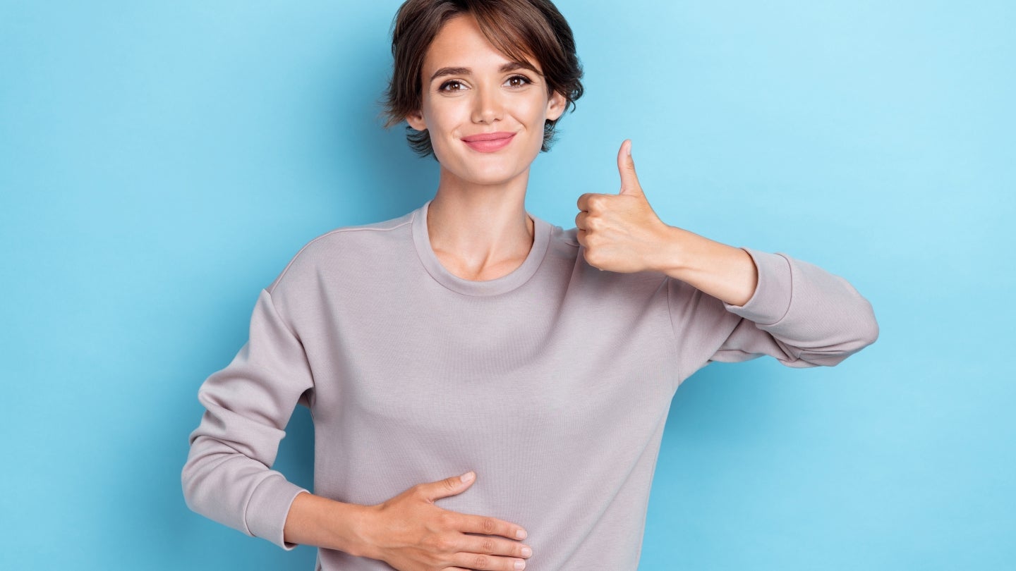Appetit anregen: Eine glückliche Frau, die ihre Hand auf ihrem Bauch hat.