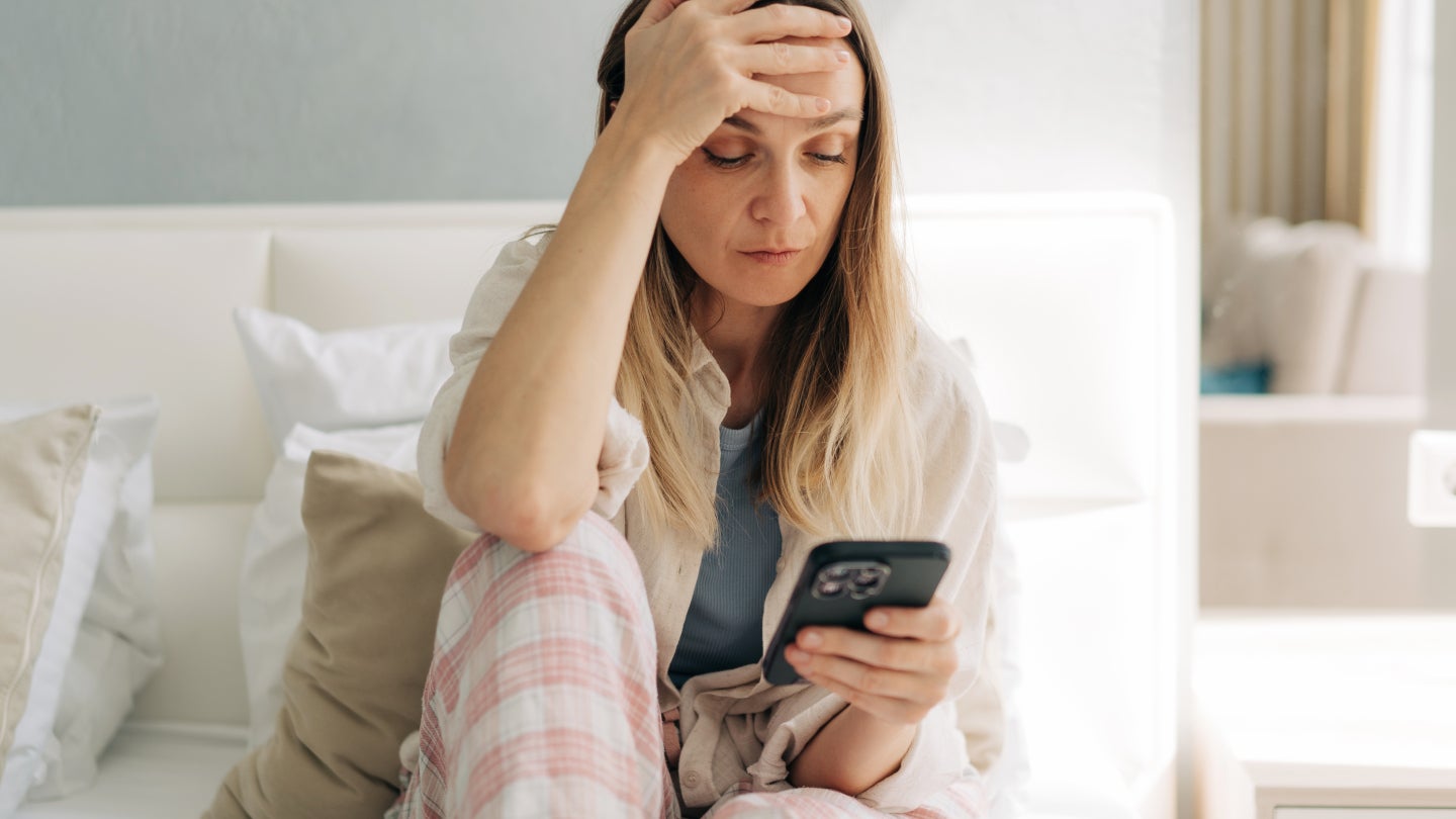 Frau schaut gestresst auf ihr Handy
