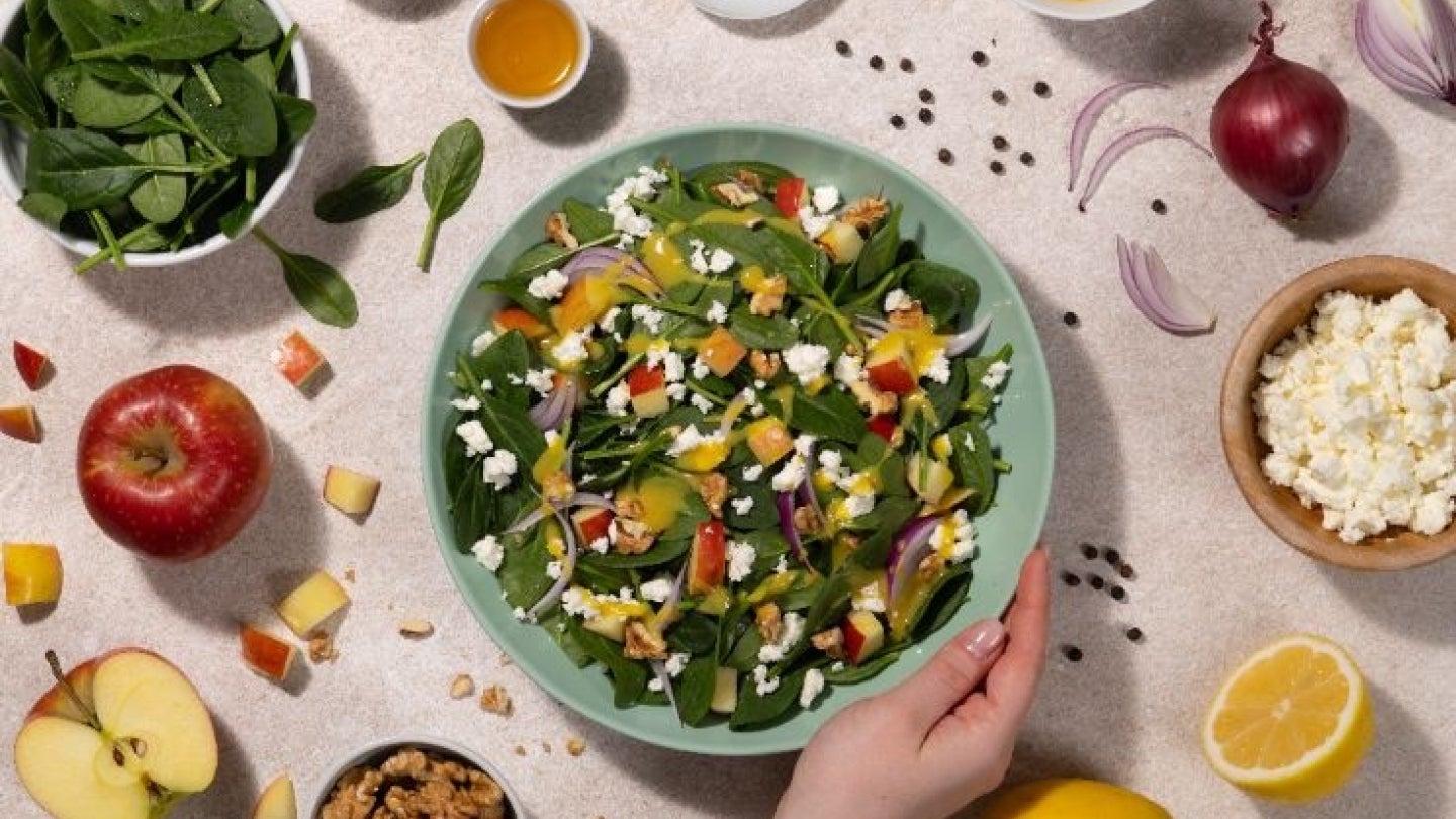 Salatbowl mit Hand und frischen Zutaten
