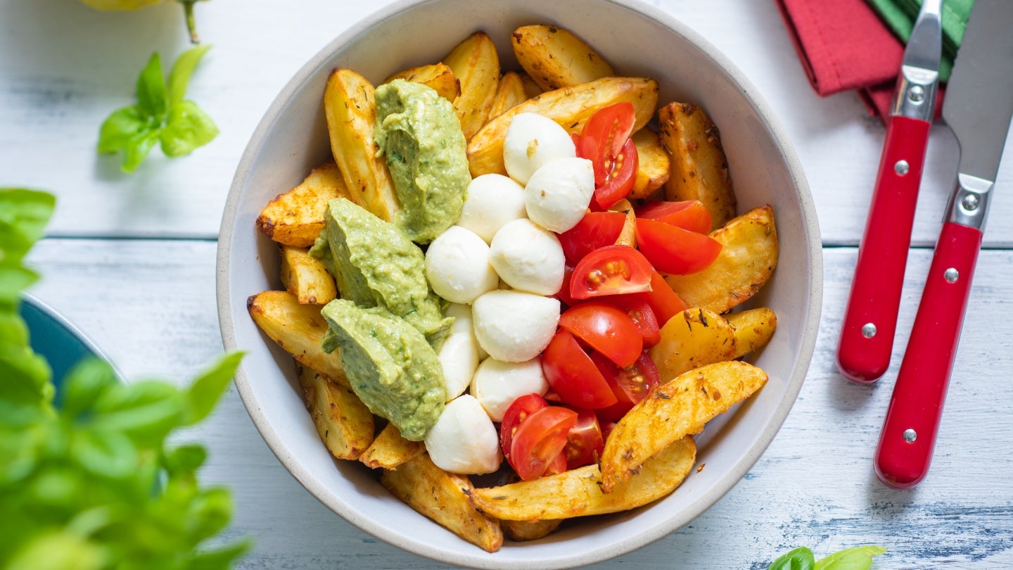 Kartoffelspalten angerichtet mit Pesto, Mozzarella und Tomaten