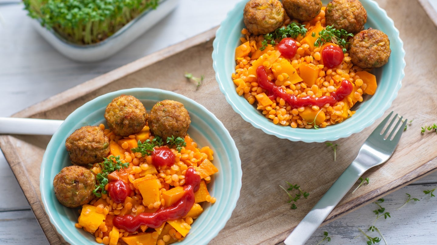 Rote Linsen Bowl mit Gemüsebällchen und Ketchup Gesicht Rote Linsen Bowl mit Gemüsebällchen und Ketchup Gesicht
