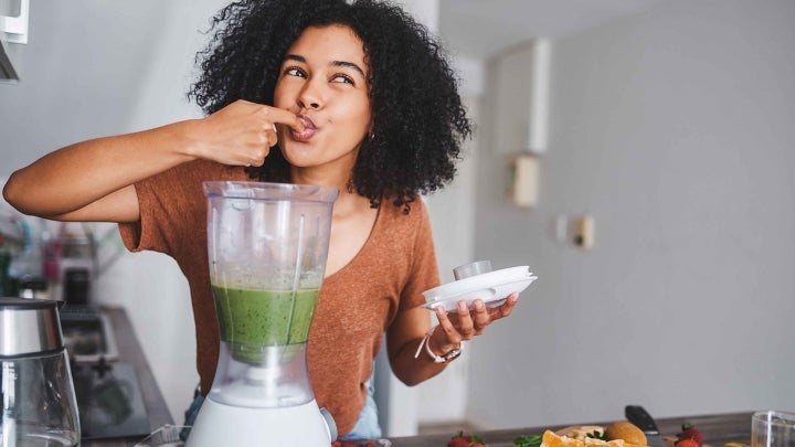 Frau macht Smoothie im Mixer