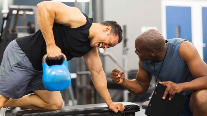 Personaltrainer feuert Mann beim Gewichtheben an