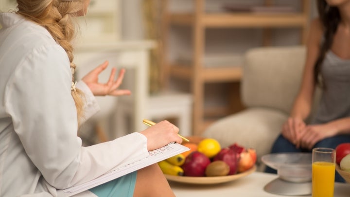 Eine Ernährungsberaterin sitzt am Tisch mit einer Patienten.