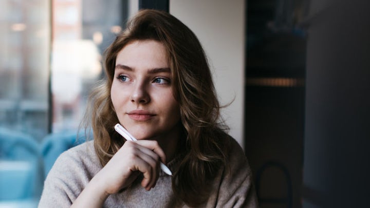 Frau sitzt am Fenster, denkt