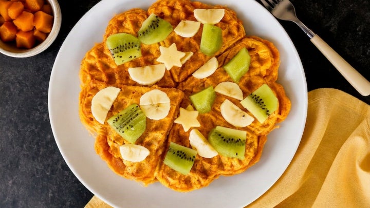Angerichtete Süßkartoffelwaffeln mit Banane und Kiwi auf einem Teller