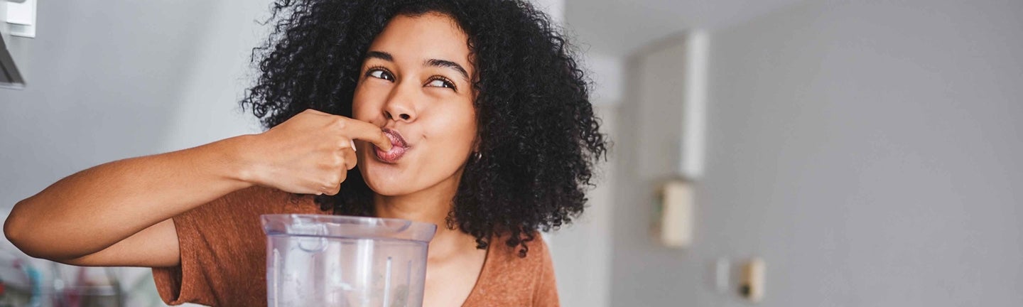 Frau macht Smoothie im Mixer