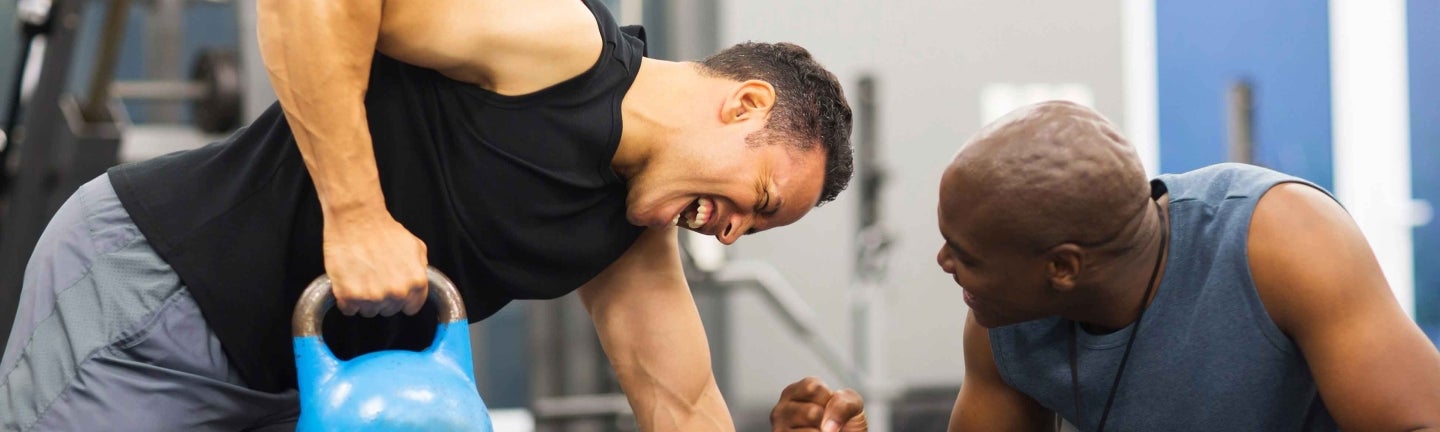 Personaltrainer feuert Mann beim Gewichtheben an