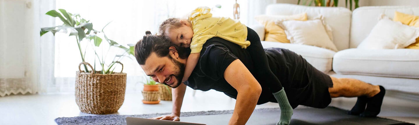 Ein Mann, der Liegestütze macht, mit einem Mädchen auf ihm.