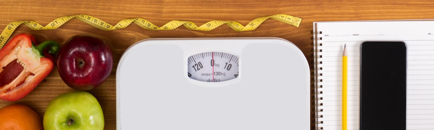 Tisch mit Obst, Waage, Block und Stift mit Überschrift BMI