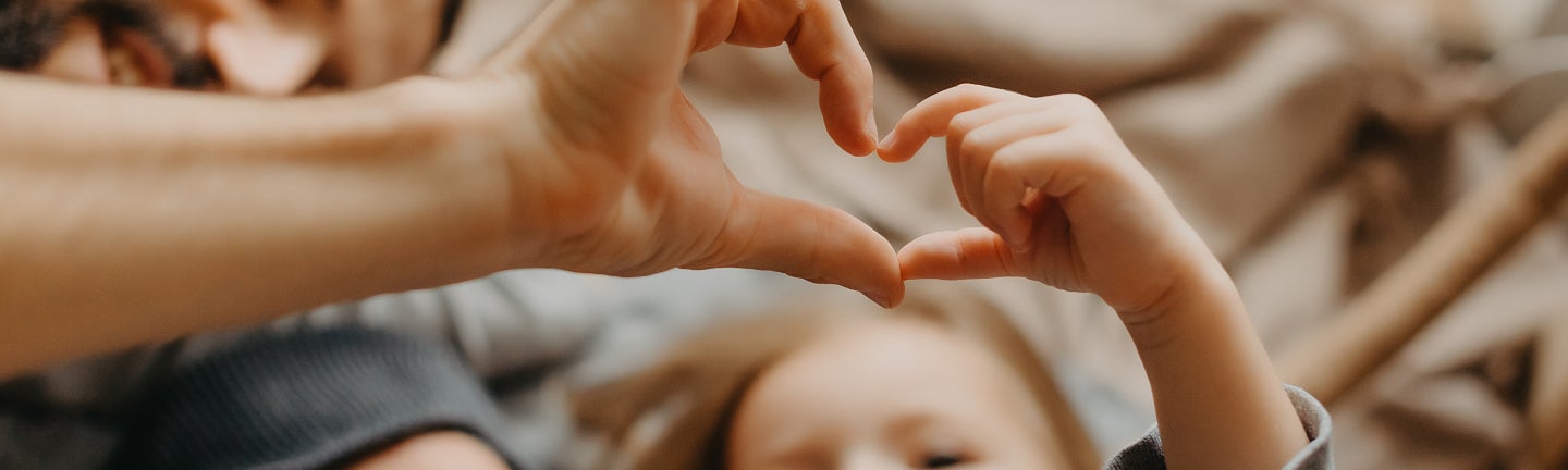 Kind formt Herz mit Hand