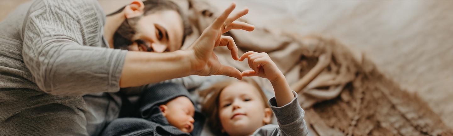 Kind und Vater formen Herz mit ihren Händen