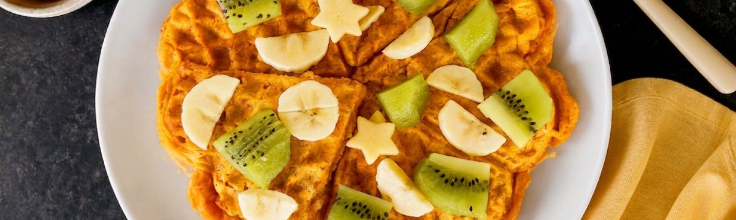 Angerichtete Süßkartoffelwaffeln mit Banane und Kiwi auf einem Teller