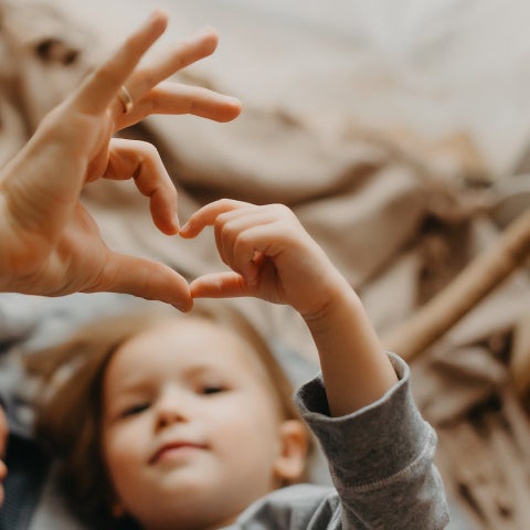 Kind formt Herz mit Hand