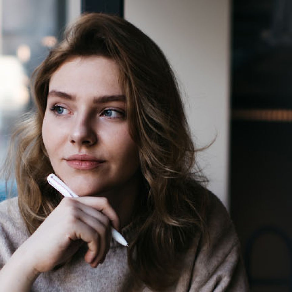 Frau sitzt am Fenster, denkt